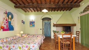 Une pièce comprenant un lit, une table avec des chaises, une cheminée et un tableau au mur.
