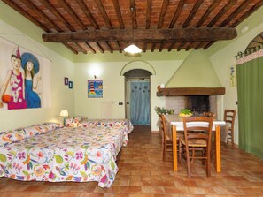 Ein Zimmer mit einem Bett, einem Tisch mit Stühlen, einem Kamin und einem Gemälde an der Wand.