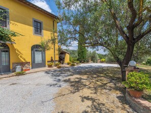 A yellow building with a gravel driveway, a tree, and potted plants. - Apartment Rosa by Interhome (Campiglia Marittima)