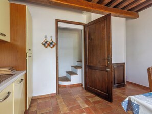 Una cuina amb armaris de fusta, taulell i sòl de rajola.