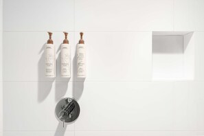 Kylpyhuoneessa on kolme pulloa Avedan rosmariini-minttushampoota ja -hoitoainetta sekä moderni suihkupää.