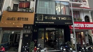 A multi-story building with a ground-floor Elegant Hotel, a visible storefront with a sign, and a school building to the right. - Elegant Hotel (Hanoi)