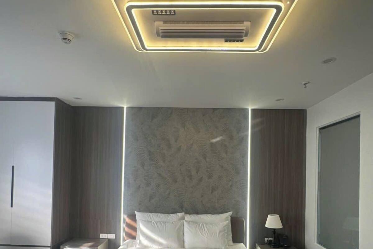 A modern bedroom with a large bed, a nightstand, a lamp, and a wardrobe.