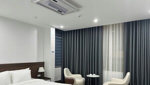 A hotel room with a bed, two armchairs, a small table with cups, and a window with curtains. - Elegant Hotel (Hanoi)