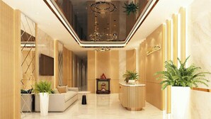 A modern hotel lobby with a reception desk, seating area, and a chandelier. - Elegant Hotel (Hanoi)