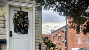 Uma casa com porta branca, caixa de correio preta e o número 27 na caixa de correio.