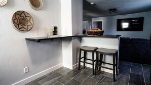 Uma cozinha moderna com bancada preta, dois banquetes e uma cesta sobre a bancada.