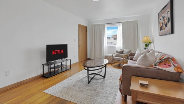 A modern living room with a flat-screen TV, a round coffee table, a sofa, and a small wooden side table. - Beautiful 2-bedroom apartment with AC in vibrant Columbus (Columbus)