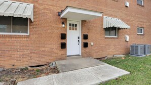 A brick building with a white door, awnings over windows, and an air conditioning unit. - Beautiful 2-bedroom apartment with AC in vibrant Columbus (Columbus)
