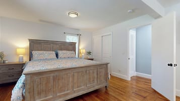 A bedroom with a wooden bed, a nightstand, a lamp, and a window with curtains.
