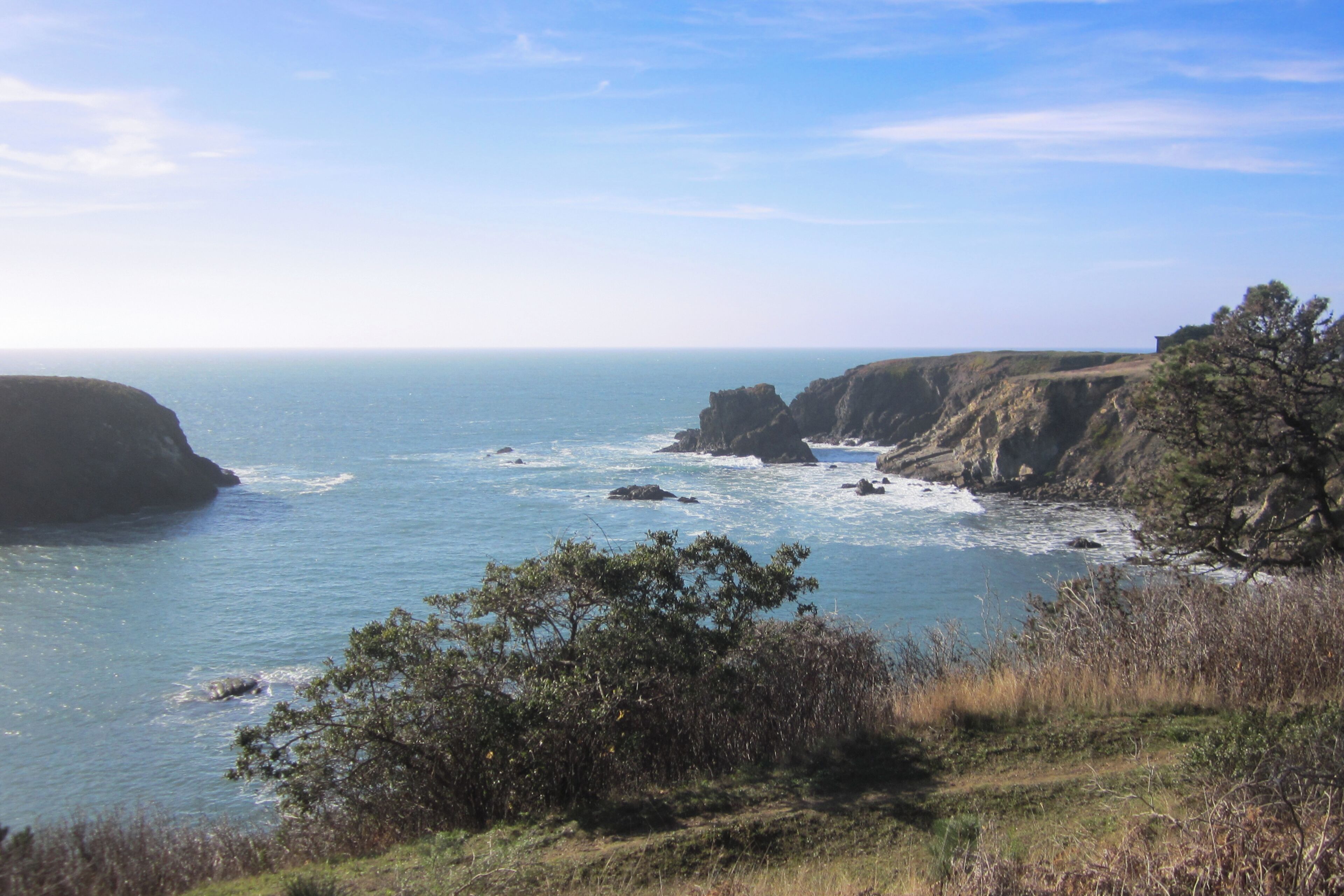Un paysage côtier caractérisé par des falaises, l’océan et la végétation.