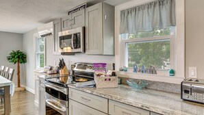 A kitchen with a built-in oven, microwave, and toaster, a window with a view of trees, and a 'Welcome' sign above the cabinets. - Coastal York Gem Near Beach: Work, Play & Explore! (York)