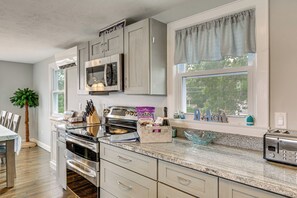 A kitchen with a built-in oven, microwave, and toaster, a window with a view of trees, and a 'Welcome' sign above the cabinets. - Coastal York Gem Near Beach: Work, Play & Explore! (York)