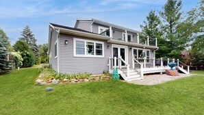 A two-story house with a covered front porch, a small deck, and a well-maintained lawn. - Lakefront + Dock! Family-Friendly Wisconsin Escape (Lodi)