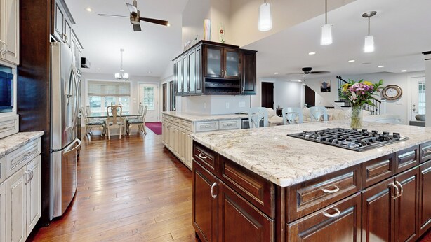 A spacious kitchen with wooden cabinets, a large island, and a dining area with a table and chairs. - Lakefront + Dock! Family-Friendly Wisconsin Escape (Lodi)