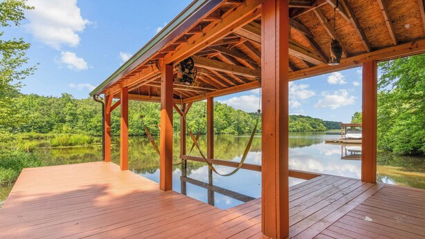 Una terraza de madera con vistas despejadas a un lago y colinas boscosas.