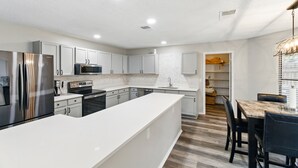 Una cocina moderna con armarios blancos, electrodomésticos de acero inoxidable y una isla central.