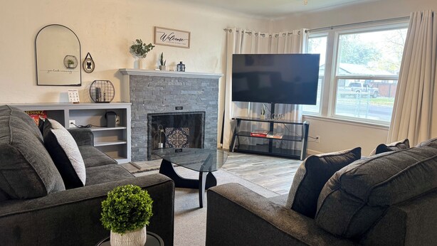 A living room with a fireplace, a flat-screen TV, and grey sofas.