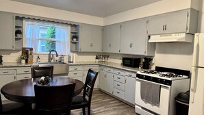 A kitchen with white cabinets, a gas stove, a microwave, and a sink.