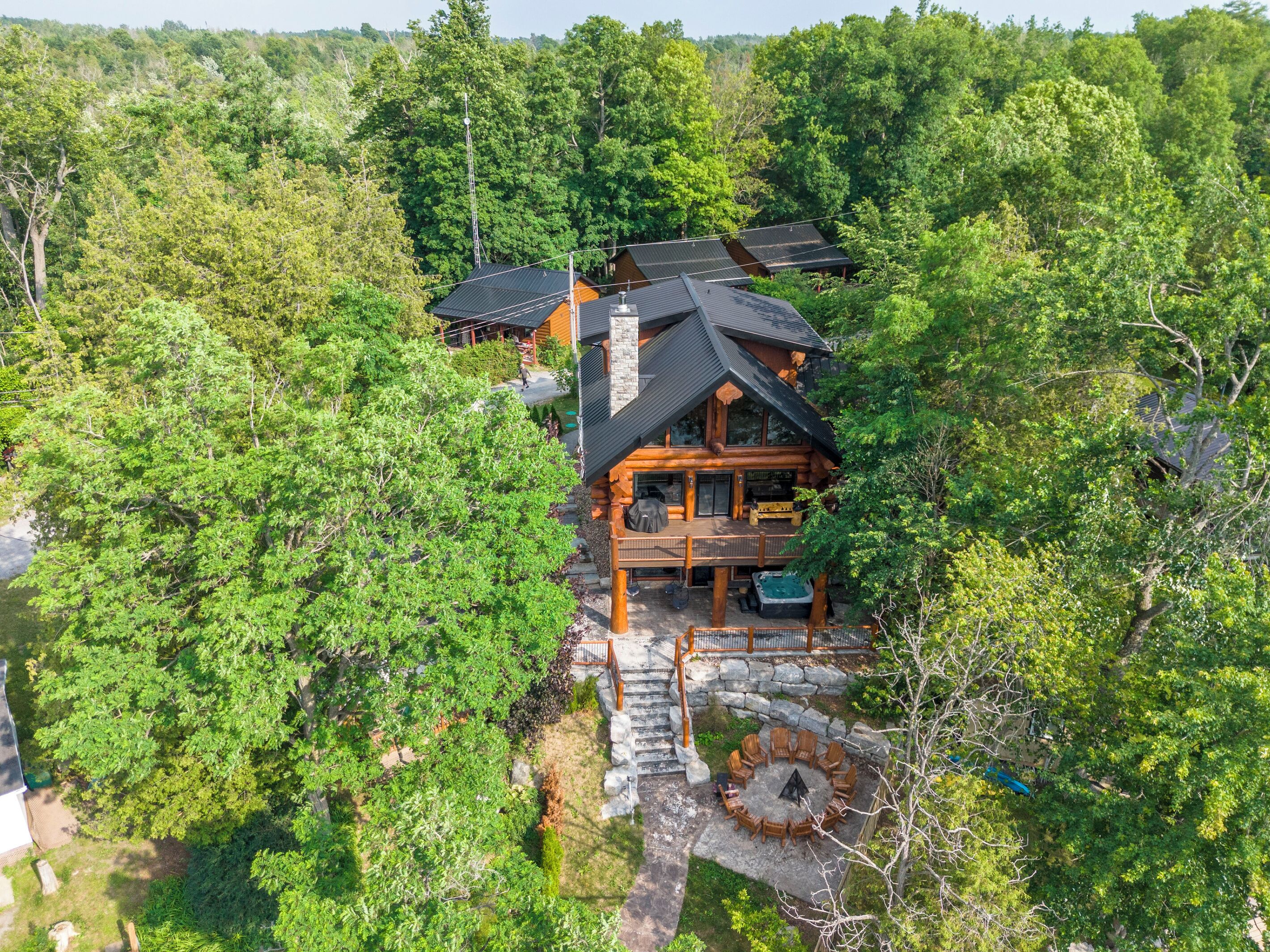 A log cabin with a deck, surrounded by dense forest.