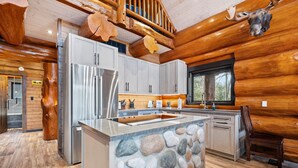 Una cocina de estilo rústico moderno con una isla de piedra, electrodomésticos de acero inoxidable y detalles de madera.