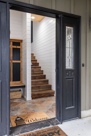 A wooden staircase leading to a room with white walls and a dark door. - The Treasure Trove - A Dog-Friendly Waterview Gem (Grapeview)