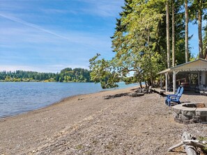 A lakeside property with a covered seating area and outdoor furniture. - The Treasure Trove - A Dog-Friendly Waterview Gem (Grapeview)