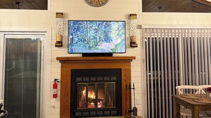 Un interior acogedor con chimenea, televisor montado y techo de madera.