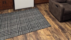 Una cocina con armarios de madera, un refrigerador blanco, un microondas, un lavamanos y una silla marrón.