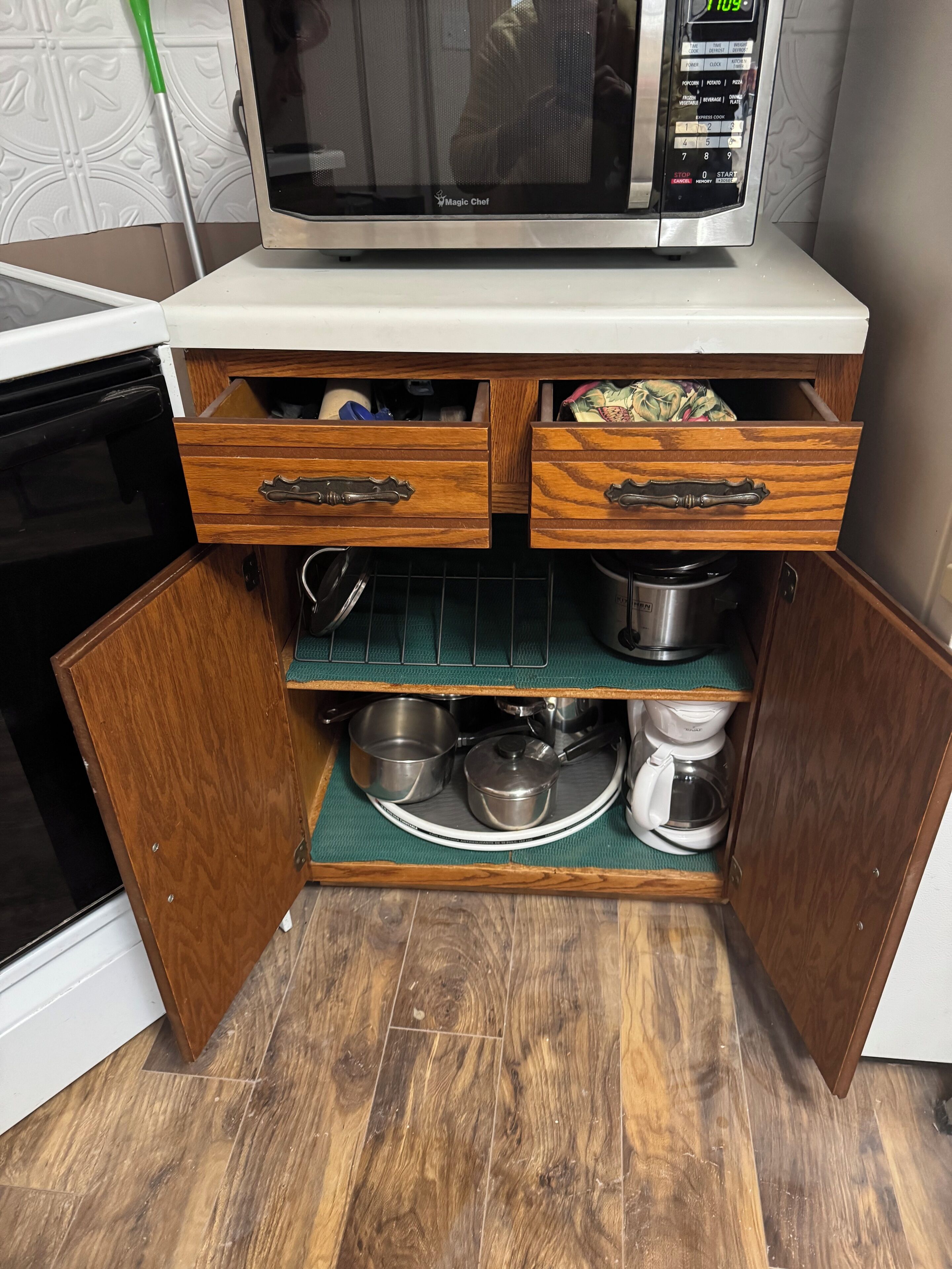 A kitchen with a microwave, wooden drawers, and a built-in oven.