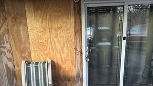 Un patio cubierto con puerta corrediza de vidrio, una silla metálica y suelo de concreto.