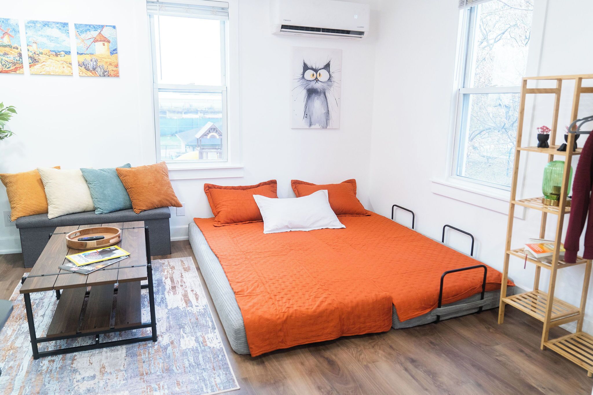 A modern bedroom with a bed, a sofa, a coffee table, and a shelf.