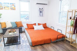 Et moderne soveværelse med seng, sofa, sofabord og reol.