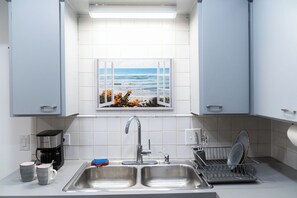 A kitchen with a window view of the ocean, a coffee maker, and a dish rack.