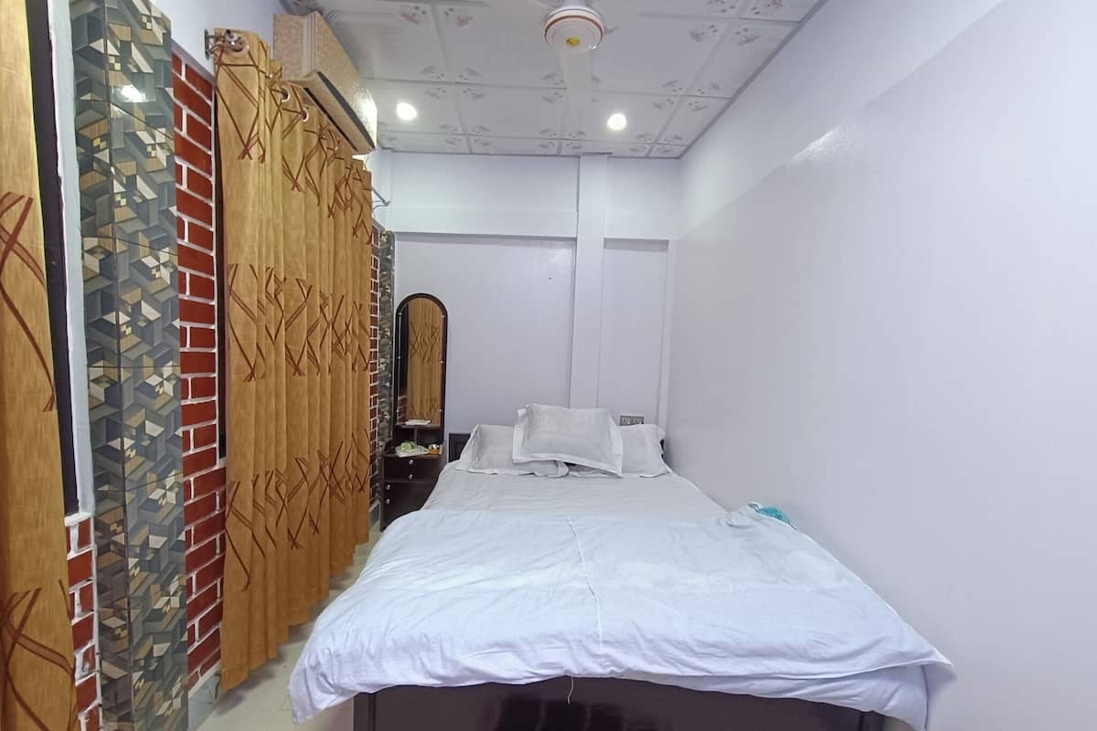 A bedroom with a bed, a nightstand, a mirror, and a ceiling fan.
