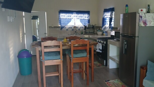 A compact kitchen with a dining table, chairs, a refrigerator, and a microwave. - 2 bedroom apartment with AC inDangriga (Dangriga)