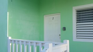 A green building with a white door and window with blinds. - 2 bedroom apartment with AC inDangriga (Dangriga)