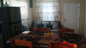 A compact living space with a dining table, chairs, a sofa, and a refrigerator. - 2 bedroom apartment with AC inDangriga (Dangriga)