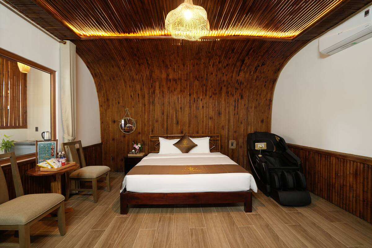 Une pièce avec un plafond en bois, un lit avec une literie blanche, un fauteuil de massage et une petite table avec des chaises.