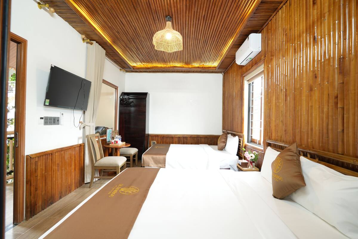 Une chambre d’hôtel avec deux lits, une télévision, un bureau avec une chaise et une fenêtre avec des rideaux.