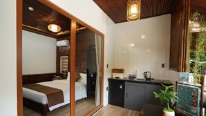 Ein modernes Hotelzimmer mit einem Bett, einer kleinen Küchenzeile und einer Schiebetür zu einem Badezimmer.
