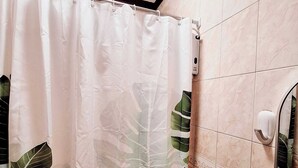 A bathroom with a shower curtain featuring a tropical leaf pattern, a toilet, and a hand soap dispenser on the wall. - EA1 Studio Apartment Room near SM City Davao Costal Road & Ecoland Bus Terminal (Davao City)