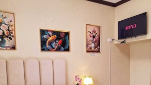 A hotel room with a bed, a TV mounted on the wall, and three framed floral paintings. - EA1 Studio Apartment Room near SM City Davao Costal Road & Ecoland Bus Terminal (Davao City)