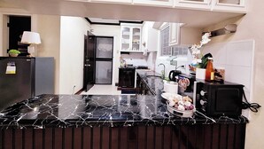 A kitchen with white cabinets, a marble countertop, and a refrigerator. - EA1 Studio Apartment Room near SM City Davao Costal Road & Ecoland Bus Terminal (Davao City)