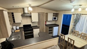 Una cucina camper compatta con angolo cottura, zona pranzo con tavolo e sedie, e un divano in primo piano.