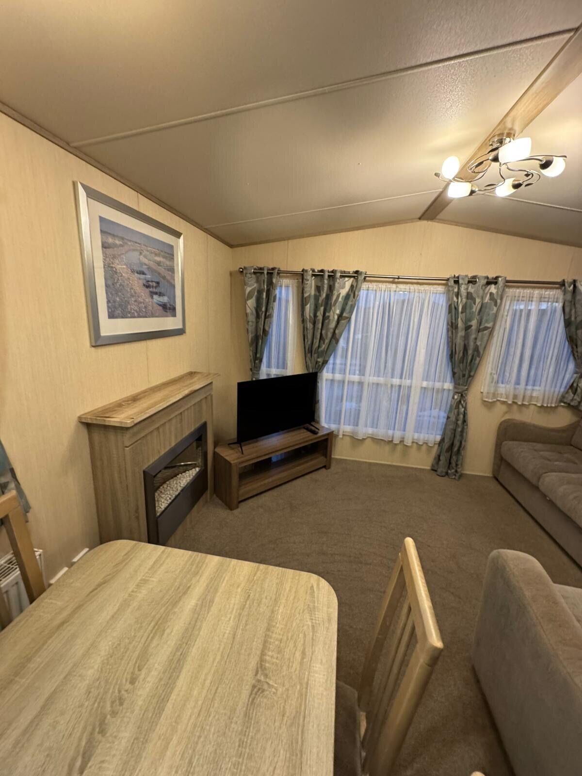 Una sala de estar con chimenea, televisor sobre un mueble de madera, sofá y mesa de comedor.