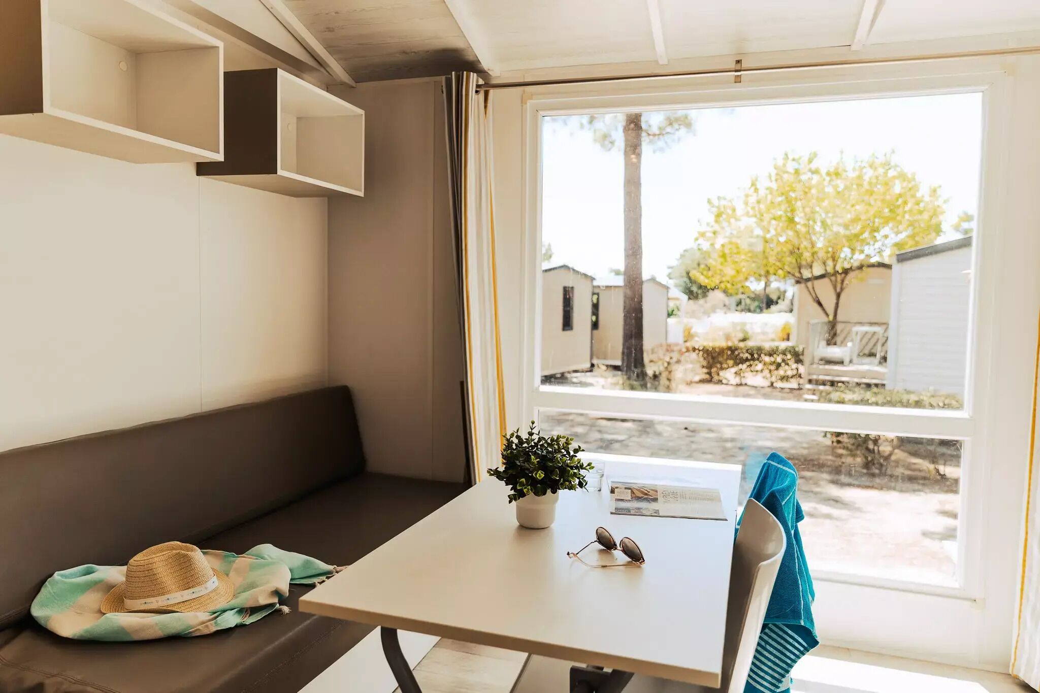A cozy interior with a bench, a table with a potted plant, and a window offering a view of the outside.