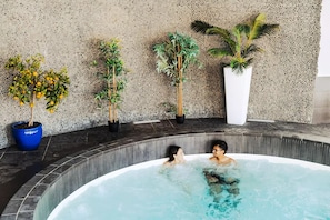 Ein Whirlpool mit zwei Personen, umgeben von Topfpflanzen.
