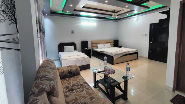 A modern bedroom with a bed, a sofa, and a small table with items on it.