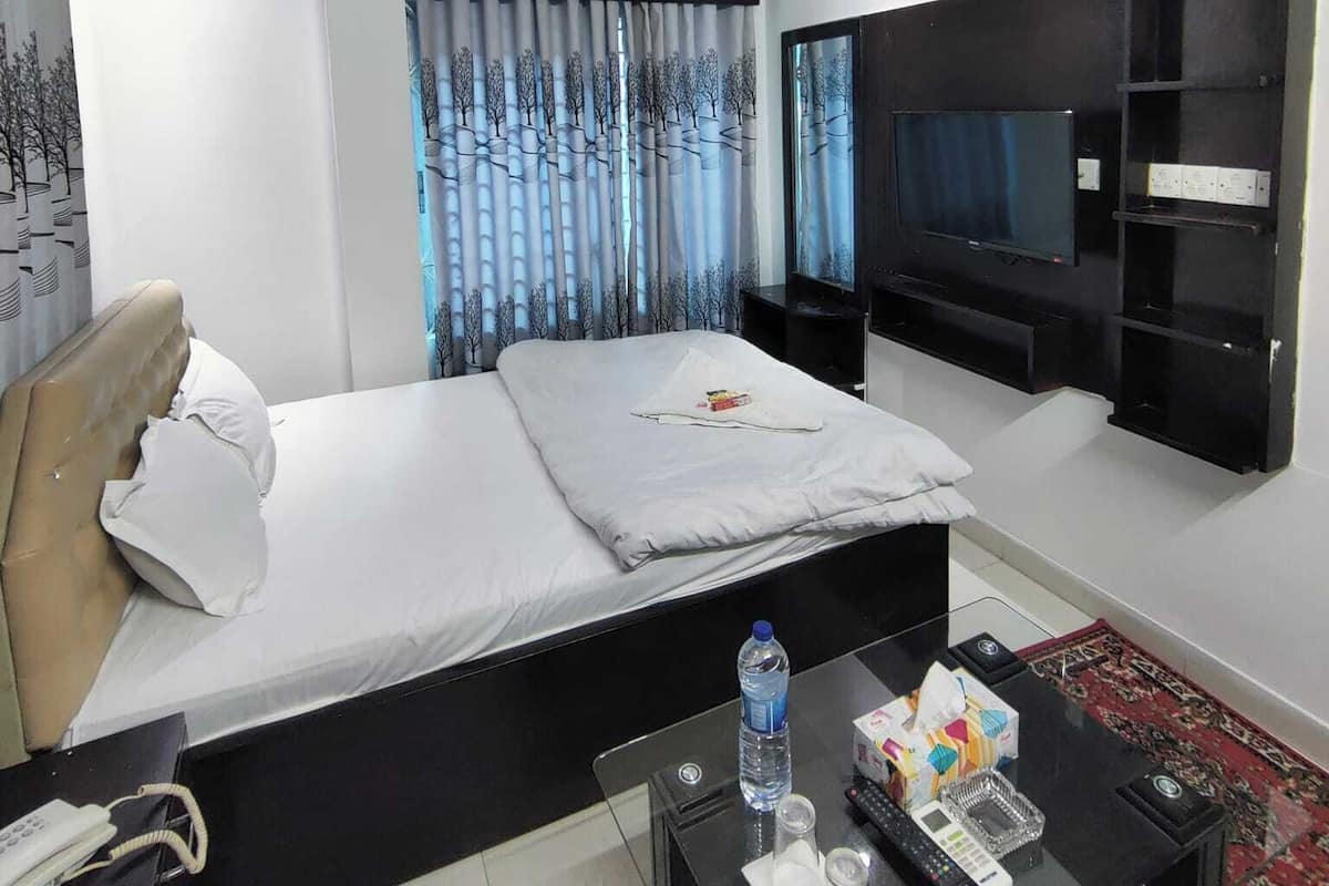 A modern hotel room with a bed, a TV, a desk with a phone, and a ceiling fan.